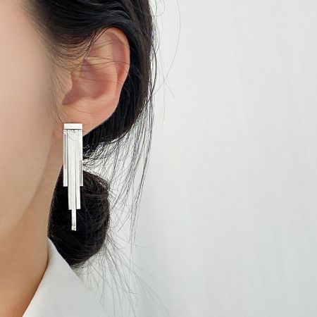 Pendientes de borlas anchas de plata esterlina 925 al por mayor - Una mujer que lleva los elegantes pendientes de borlas anchas de plata esterlina 925, mostrando su longitud y brillo.