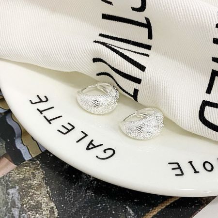 La versione in argento sterling 925 degli orecchini a cerchio spessi elegantemente presentata su un piatto decorativo.