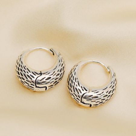 Close-up of the intricate design on the unique silver hoop earrings.