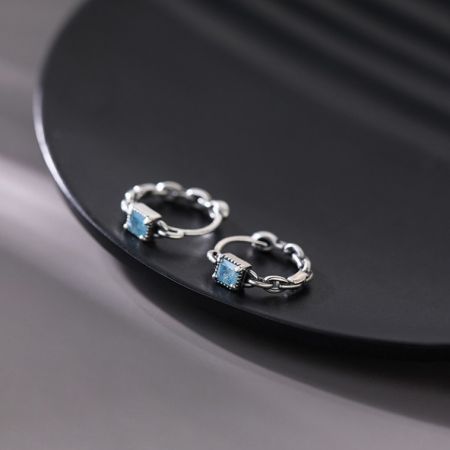 Orecchini a perno geometrici a cubo di menta in argento sterling 925 - Un paio di orecchini a perno geometrici a cubo di menta in argento sterling 925 con gemme di zirconia cubica blu scintillanti su uno sfondo bianco.