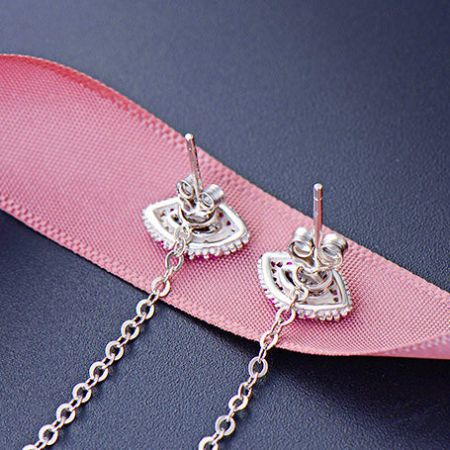 Gli orecchini con nappina in argento sterling presentati elegantemente su un nastro rosa.