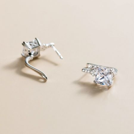 Un paio di orecchini quadrati in argento sterling che mostrano le brillanti pietre chiare su uno sfondo bianco.