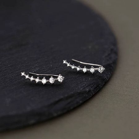 Vista dettagliata degli orecchini a climber in argento sterling su uno sfondo scuro, evidenziando gli zirconi scintillanti.