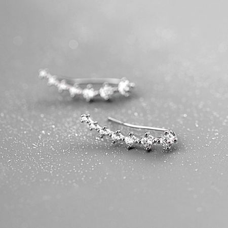 Orecchini a perno a climber in argento sterling 925 con sette zirconi scintillanti (5 paia) - Un paio di orecchini a perno a climber in argento sterling 925 con sette zirconi scintillanti, elegantemente curvati e esposti su uno sfondo neutro.