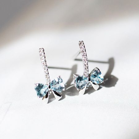 Pendientes de botón de lazo azul de circonita cúbica de plata esterlina 925 al por mayor. - Un par de pendientes de botón de lazo de plata esterlina 925, cada uno con una piedra preciosa de circonita cúbica azul claro en el centro y acentuado con cristales transparentes.