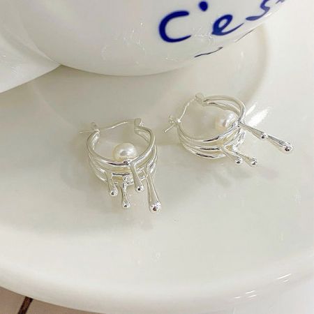 Un'angolazione alternativa degli orecchini a goccia di perla in argento, che mette in mostra l'intricato lavoro in metallo fluido.