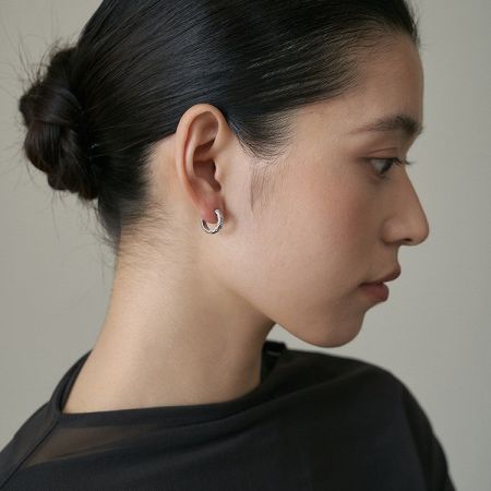 Profilo laterale di un modello che indossa gli orecchini a cerchio trapuntati classici, dimostrando il loro fascino versatile.