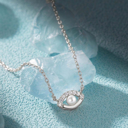 Artistic shot of the silver evil eye pendant necklace resting on a blue stone.