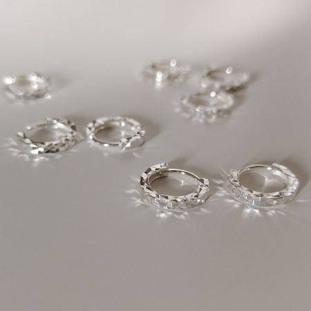 Orecchini a gancio in argento sterling 925 con taglio a diamante - Un paio di orecchini a gancio in argento sterling 925 con taglio a diamante che mostrano la loro intricata texture sfaccettata su uno sfondo bianco.