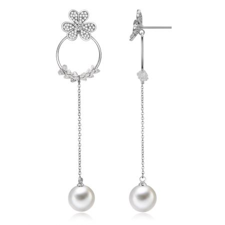 Vista en primer plano de los pendientes largos en forma de trébol, destacando el intrincado diseño floral con zirconias cúbicas brillantes y una gran perla blanca.