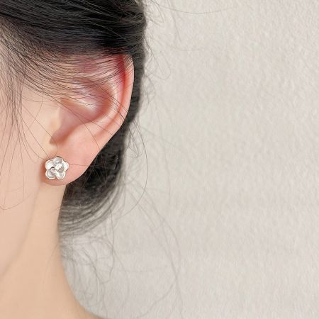 Un modèle portant la délicate boucle d'oreille en fleur en émail blanc et or.