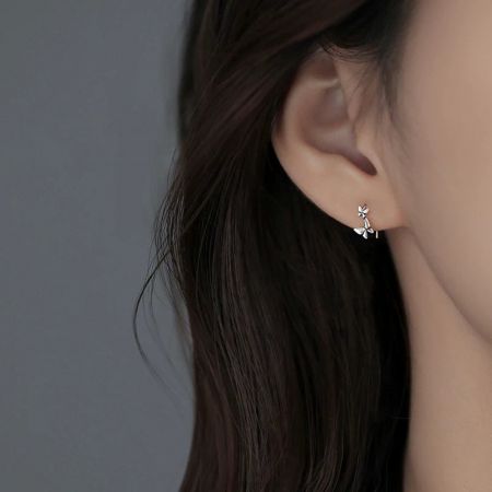Una modella che mostra un orecchino a gancio a forma di fiore in argento sterling, enfatizzando la sua vestibilità comoda e il look alla moda.