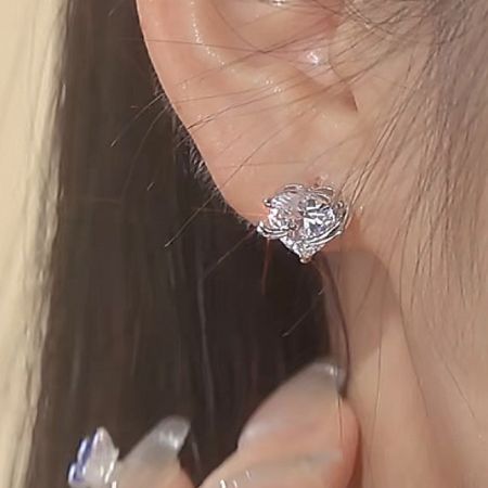 Un modello che indossa gli orecchini a perno in zirconia a forma di cuore argentato, mostrando la loro scala e brillantezza.
