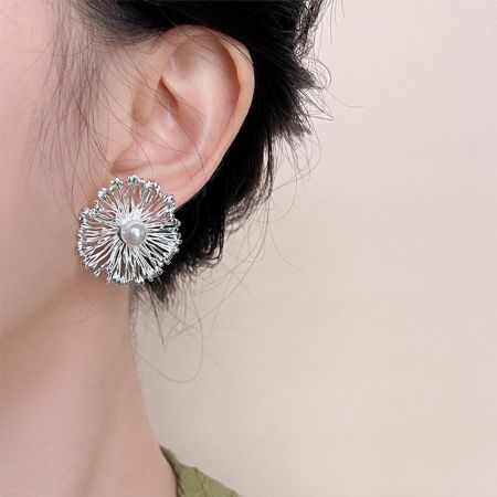 Modèle portant des boucles d'oreilles florales affirmées avec un centre en perle, mettant en valeur leur taille et leur style.