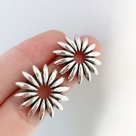 Orecchini a bottone vintage a girasole retro in argento sterling 925 (5 paia) - Una mano che tiene un paio di orecchini a bottone retro a girasole in argento sterling 925, parte di un set di orecchini a fiore di margherita cavo vintage.