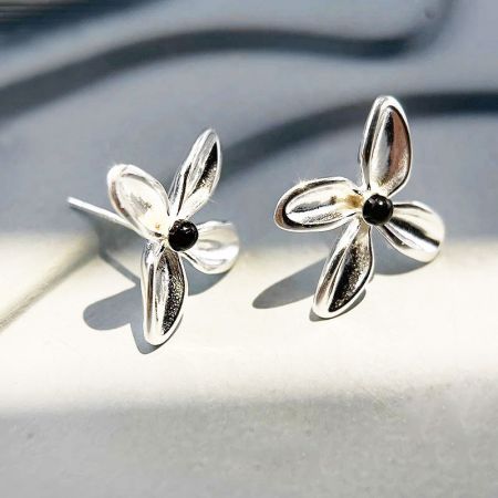 Orecchini a bottone a forma di fiore in onice nero semplice in argento sterling 925 (5 paia) - Un primo piano di un paio di orecchini a bottone a forma di fiore in argento sterling 925 con centri in onice nero lucido, su uno sfondo bianco pulito.
