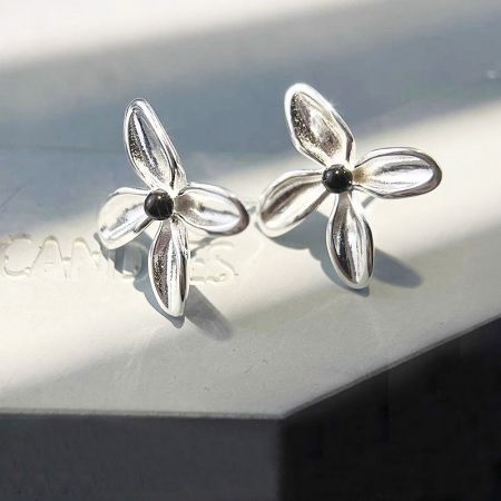 Vista dettagliata degli orecchini a bottone a forma di fiore in argento sterling con quattro petali e un centro in onice nero.