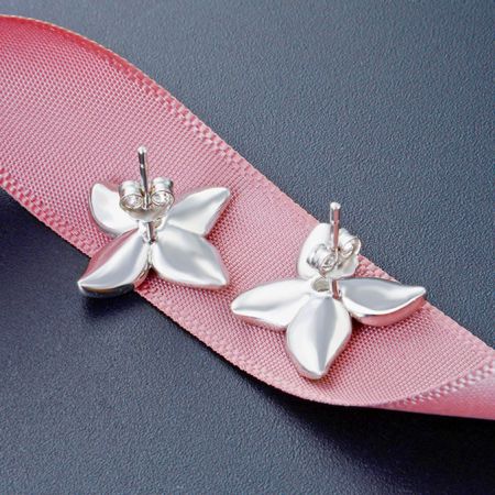Un paio di orecchini a forma di fiore in argento elegantemente esposti su un nastro rosa, che mostrano il loro design delicato.