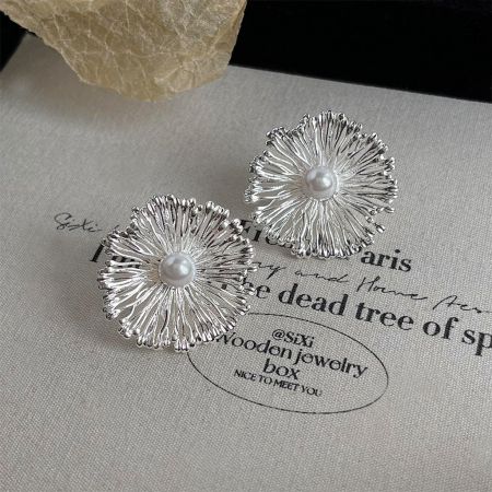 Boucles d'oreilles florales en laiton de style designer avec centres en perle, présentées sur un fond neutre.