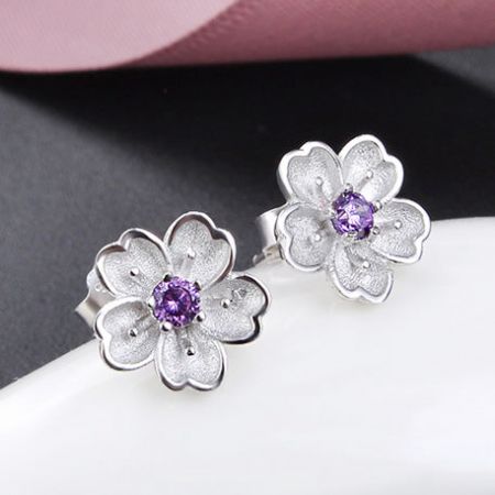 Close-up view of the sterling silver flower earring with a central purple gem.