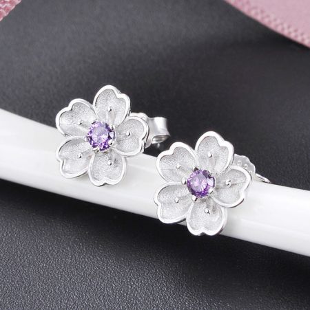 Angled shot of the cherry blossom earrings, highlighting the petal details.