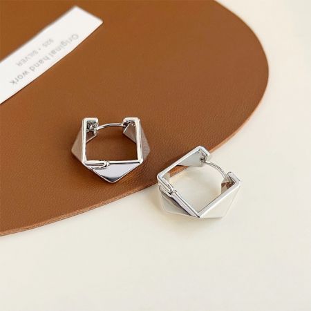 銀メッキの幾何学的フープイヤリングの詳細なビューで、ユニークなデザインを強調しています。
