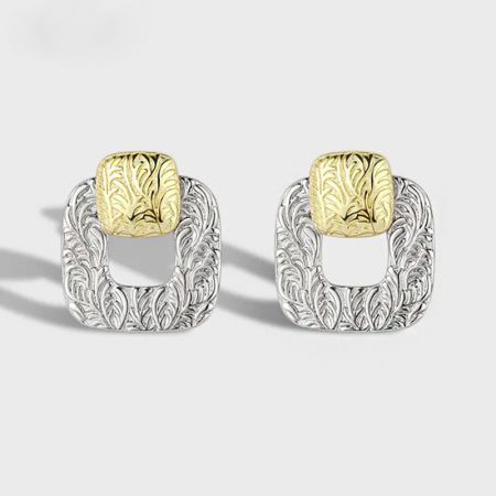 Un paio di orecchini a bottone quadrati in argento sterling 925 con intricati motivi in oro e argento.