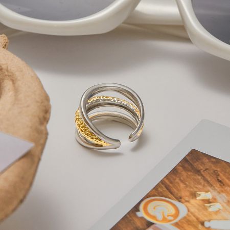 Close-up productfoto van een meerlaagse roestvrijstalen ring met zowel gepolijste zilveren als gestructureerde gouden banden.