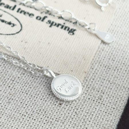 Un autre angle du collier en argent 'Bonne Chance', montrant la chaîne et le fermoir.