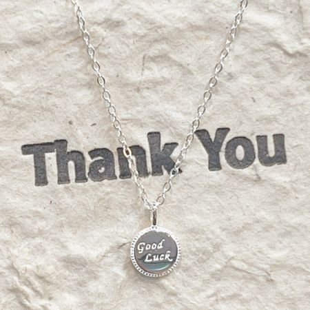Le collier en argent sterling 'Bonne Chance' présenté sur une carte 'Merci', parfait pour offrir.