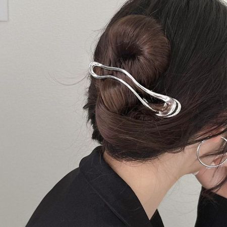 Un chic clip de garra de metal plateado que sostiene el cabello de una mujer en un elegante moño.
