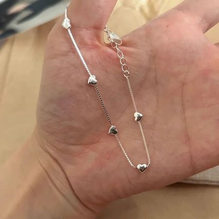 Detaljerad vy av de polerade hjärtcharmsen på den fina kedjan i sterling silver.