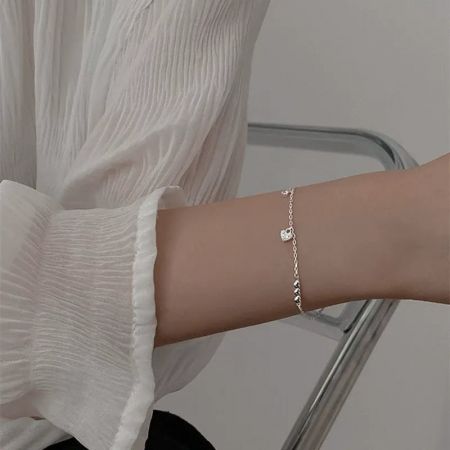 925 Sterling Zilveren Verbonden Harten Bedelarmband met Cubic Zirconia - De pols van een vrouw versierd met de 925 Sterling Zilveren Verbonden Harten Bedelarmband, met de centrale hartbedel in het middelpunt.