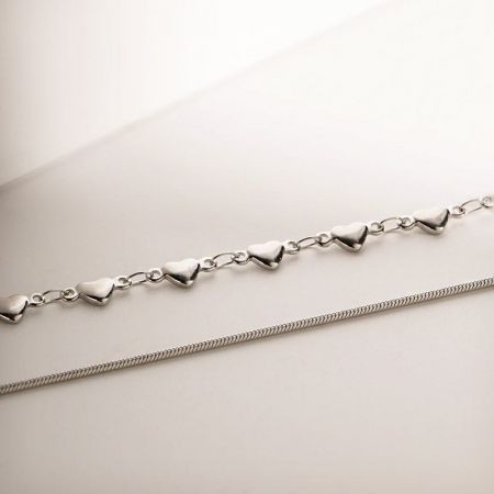 Detaillierte Aufnahme, die die herzförmige Gliederkette mit der glatten, gedrehten Kette in Silber vergleicht.