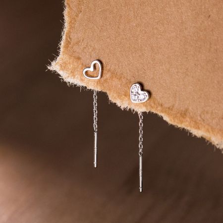 Scatto ravvicinato che confronta l'orecchino a cuore in argento semplice con la versione adornata di zirconia.