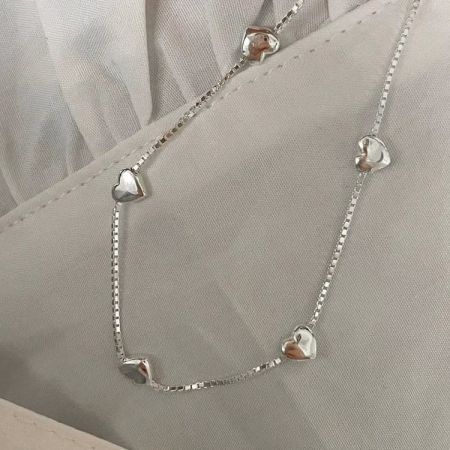 En stapel av fem minimalistiska hjärtarmband i sterling silver, perfekta för lager.