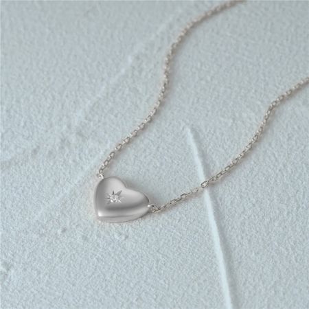 Vista dettagliata della collana con pendente a cuore d'argento con un design a raggi.