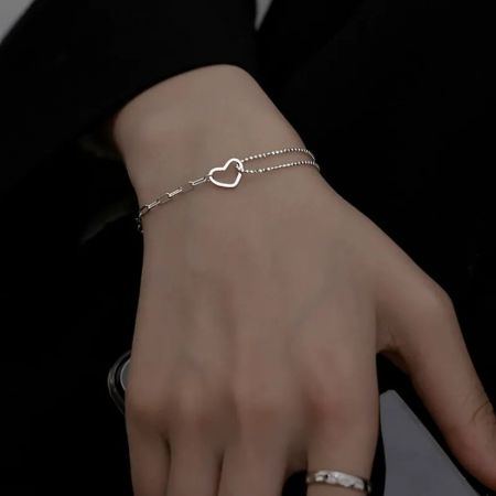Prise de vue détaillée du bracelet cœur ouvert sur un poignet, mettant en valeur la finition en argent poli.