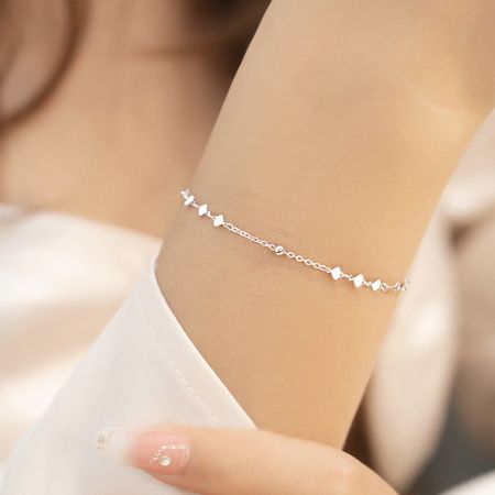 A model wearing the silver heart-shaped charm bracelet.