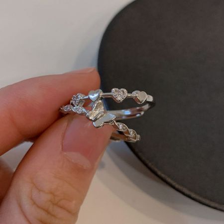 Bagues en argent sterling 925 avec papillon et cœur en CZ - Une main tenant plusieurs bagues d'amitié en argent sterling 925, mettant en valeur les délicats designs de cœur et de papillon avec des accents en zircon cubique étincelants.