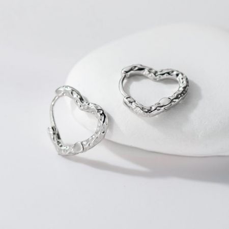 Close-up van getextureerde hartvormige creolen in 925 sterling zilver.