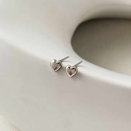 Toma detallada de los pequeños pendientes de corazón minimalistas, destacando su diseño simple.