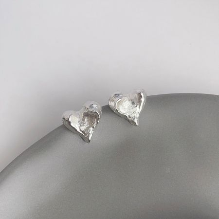 La versión chapada en plata de los pendientes de corazón irregulares, mostrando el diseño único.