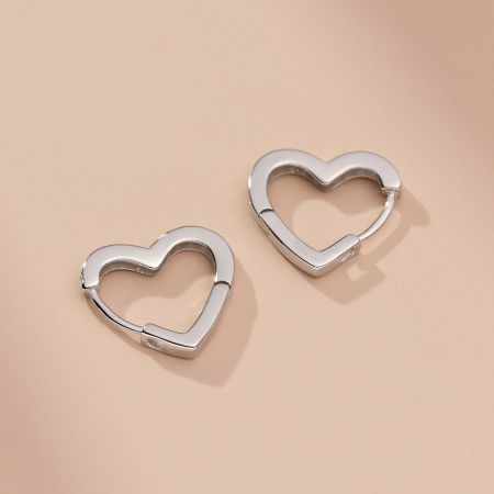 Vista angolata degli orecchini a cerchio a forma di cuore in argento che evidenzia la loro finitura lucida.