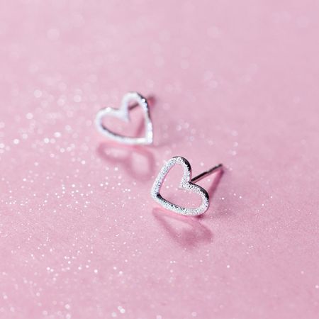 Vista ravvicinata degli orecchini a perno a forma di cuore vuoto in argento sterling.