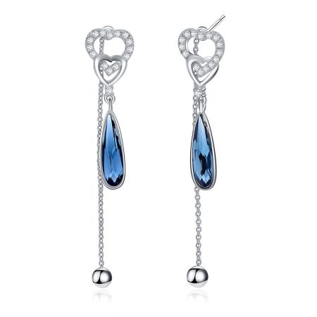 Close-up van de hartvormige bovenkant en de hangende blauwe edelsteen van de Swarovski kristal oorbellen.