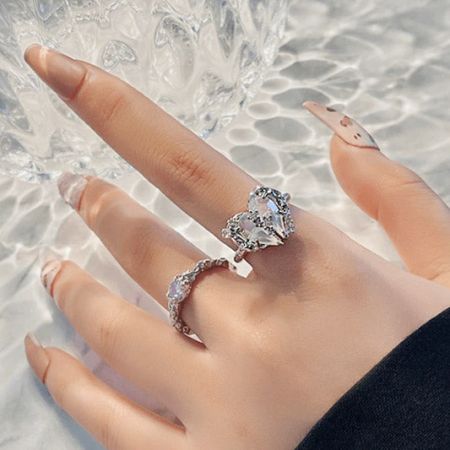 De hand van een model die een zilver vergulde ring met een prachtige opalescente hartvormige steen toont.