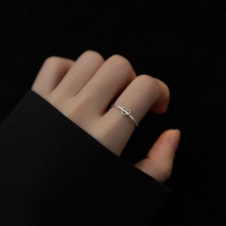 Detailed view of a silver heart ring featuring intricate diamond detailing along the band.