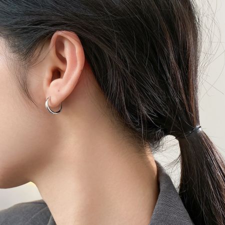 Una vista ravvicinata di una donna che indossa un orecchino a cerchio minimalista in argento sterling 925, mostrando la sua vestibilità e stile.