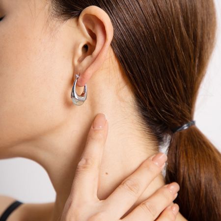 Detailed view of the silver stainless steel hoop earring on a model's ear.